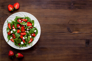 Top view of spinach salad with strawberry and goat cheese