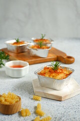 selective focus of  baked macaroni and cheese  in aluminium foil cup against white background 