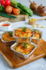 selective focus of  baked macaroni and cheese  in aluminium foil cup against white background 