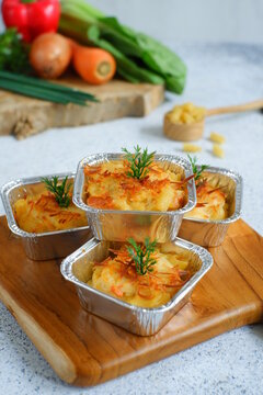 selective focus of  baked macaroni and cheese  in aluminium foil cup against white background 