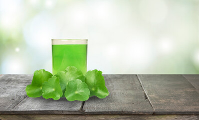 The Centella asiatica juice is in a clear glass and has green Centella asiatica leaves.