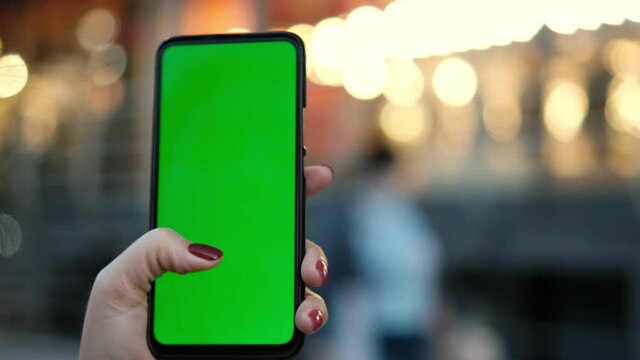 Point of View of voman at street Using Phone With Green Mock-up Screen Chroma Key Surfing Internet Watching Content Videos Blogs Tapping on Center Screen