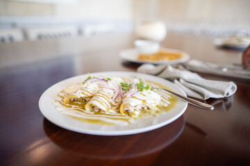 Plate with delicious green enchiladas on brown table