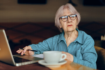 Portrait of an elderly woman in a cafe a cup of drink laptop Social networks unaltered