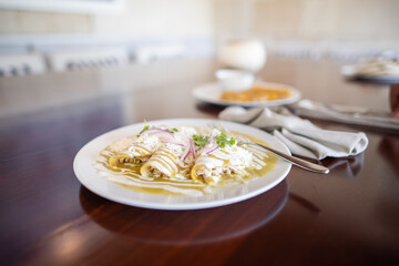 Plate with delicious green enchiladas on brown table