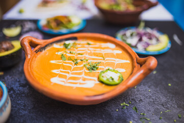 Delicious soup in traditional clay pot above dark surface