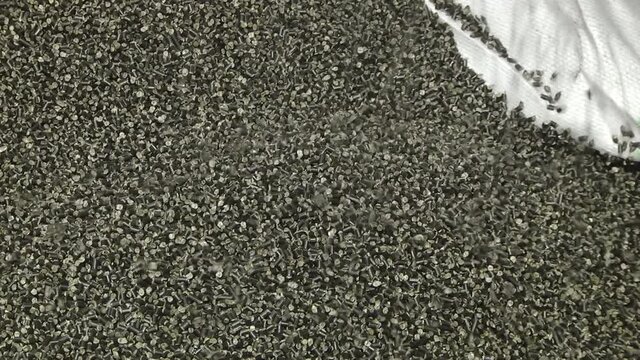 Close-up of Black plastic polymer granules. Flakes from recycled plastic bottles in a bag. Modern equipment for processing and sorting plastic waste.