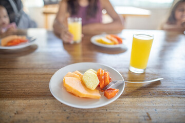 Delicious fruit slices and orange juice on wooden table with blurry background
