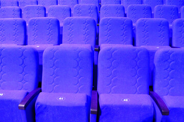 Obraz premium blue armchairs. Empty concert hall, theater chairs background ... color photo, empty cinema or concert hall. The red chairs in the cinema hall are illuminated by a light beam. Selective focus