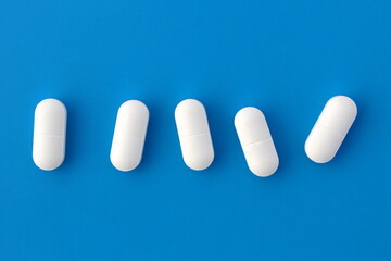 Five white oblong tablets lie on a blue background.