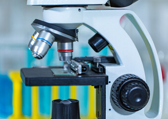 Closeup studio shot of magnifier zooming lens microscope camera placing on working table in hospital laboratory full of glassware equipment test tube rack Erlenmeyer flask beaker and computer monitor