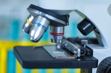 Closeup studio shot of magnifier zooming lens microscope camera placing on working table in hospital laboratory full of glassware equipment test tube rack Erlenmeyer flask beaker and computer monitor