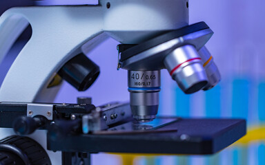 Closeup studio shot of magnifier zooming lens microscope camera placing on working table in hospital laboratory full of glassware equipment test tube rack Erlenmeyer flask beaker and computer monitor