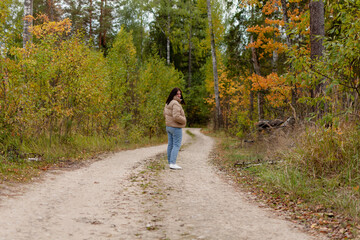 Fototapeta na wymiar cheerful young woman in a gray jacket on the background of an autumn landscape