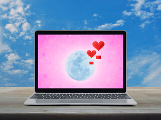 Red fabric heart love air balloon fly over moon and blur pink star screen on modern laptop computer on wooden table over blue sky with white clouds, Business internet dating online, Valentines day con