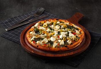 Delicious cheese stringy slice lifted of full supreme pizza baked fresh out of the oven next to ingredients