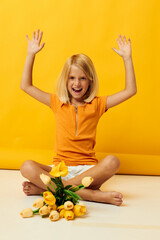 little girl sitting on the floor with a bouquet of flowers yellow background