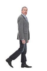 side view full length photo of a mid aged business man walking forward and looking at camera.