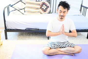 Fototapeta na wymiar ヨガをして瞑想しようとするアジア系の男性　全身