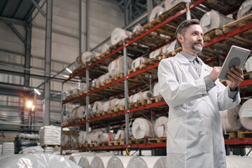 Man in white robe at factory shelves
