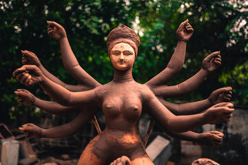 Close up of yellow colour Durga goddess idol with red clothing newly made at a workshop for the religious hindu festival. Indian goddess with multiple arms.