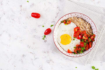 Breakfast oatmeal porridge with roasted egg and tomatoes salad. Healthy balanced food. Top view, above