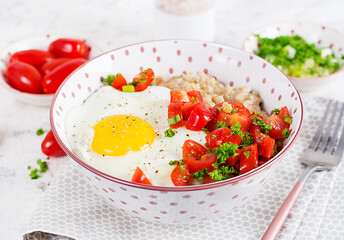 Breakfast oatmeal porridge with roasted egg and tomatoes salad. Healthy balanced food.