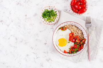 Breakfast oatmeal porridge with roasted egg and tomatoes salad. Healthy balanced food. Top view, above - obrazy, fototapety, plakaty