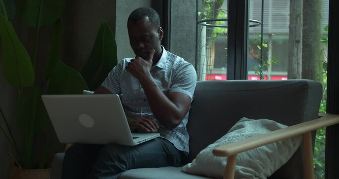 African businessman working the cafe office typing on laptop thinking planning black freelance people working indoor using computer