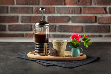 Coffee is poured into a cup from French press coffee maker , On the old wood table and black background, Natural light, Selective focus, Vintage style.