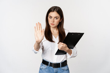 Serious woman with clipboard documents, extending arm, showing taboo stop sign, disapprove,...