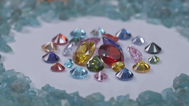 A pile of colorful diamonds of various sizes are placed in a center circle on the blue raw aquamarine stone background.. surrounded by rough blue stone background.