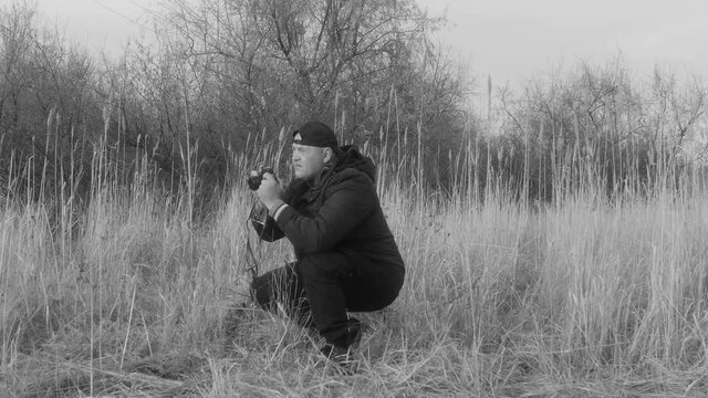 a man photographs in nature, on a retro camera, side view, in black and white