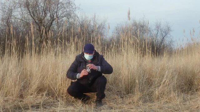 a traveler-photographer in a protective mask on his face photographs nature with a two-lens reflex camera