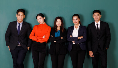 Portrait studio shot group of Asian professional male female teacher or college students in formal suit outfit standing crossed arms smiling look at camera on green chalkboard background in classroom