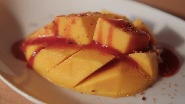 Plate of chopped mango with Mexican chamoy sauce and blurry background