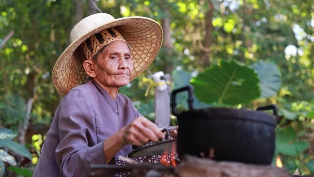 An old woman lighting a cooking fire