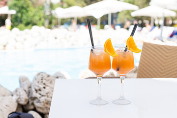 Bright orange cocktail stands on edge of pool
