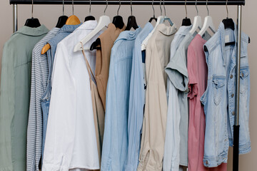 Close-up of a colorful variety of shirts, T-shirts and blouses on hangers inside the closet. boutique of pastel-colored clothing. organic cotton clothing. Selective focus.