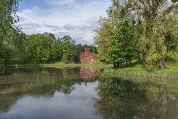 Fototapeta na wymiar parks pond on spring day with small brick chapel afar