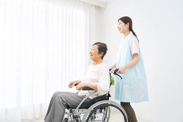 車椅子に乗る高齢者と介護士　屋内