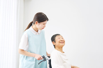 Obraz premium 車椅子に乗る高齢者と介護士 屋内