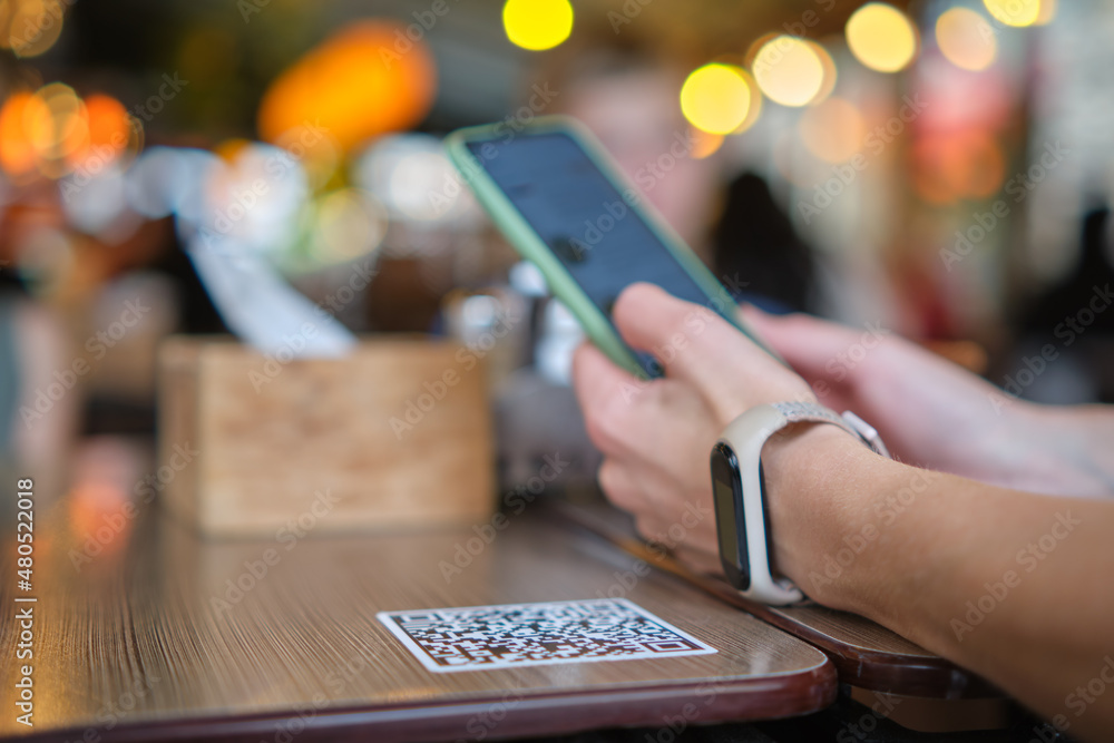 Wall mural closeup of guest hand ordering meal in restaurant while scanning qr code with mobile phone for onlin