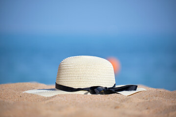 Closeup of yellow straw hat on sandy beach at tropical seaside on warm sunny day. Summer vacation concept