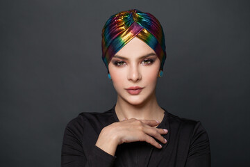 Young modern fashionable elegant woman in turban on black background