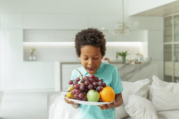 Little boy eating fruit at home, studio shot