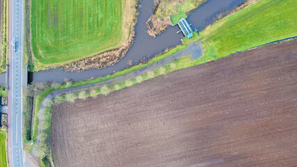 Top down view, shot with a drone of the Landscape with road and bridges over the river Aa, Herentals, Belgium, running amongst the farmfields. High quality photo