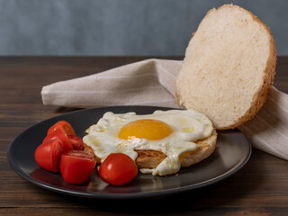 Fried egg with red cherry tomatoes between slices of a bun with sesame seeds