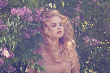 Blonde young woman with long wavy hair on blossom flowers background