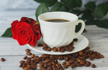 White cup of coffee, coffee beans and red roses on light gray background. Romantic breakfast concept.